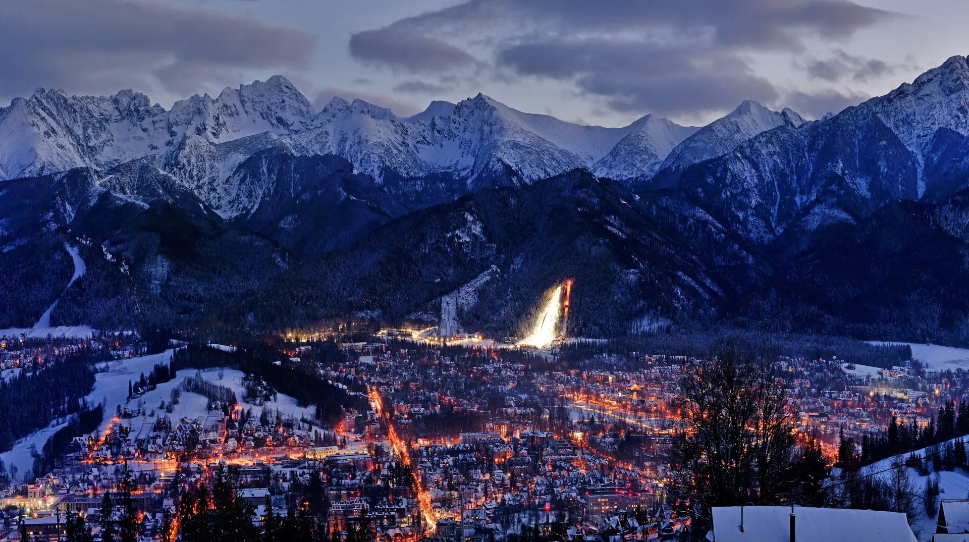 Zakopane at night in winter, with the floodlit Wielka Krokiew ski jump and the Tatra range behind