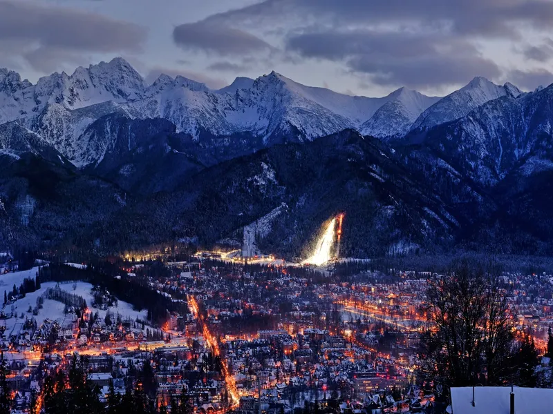 Zakopane at night in winter, with the floodlit Wielka Krokiew ski jump and the Tatra range behind